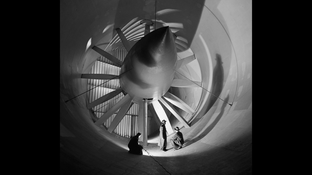 Two men in front of Altitude Wind Tunnel drive fan