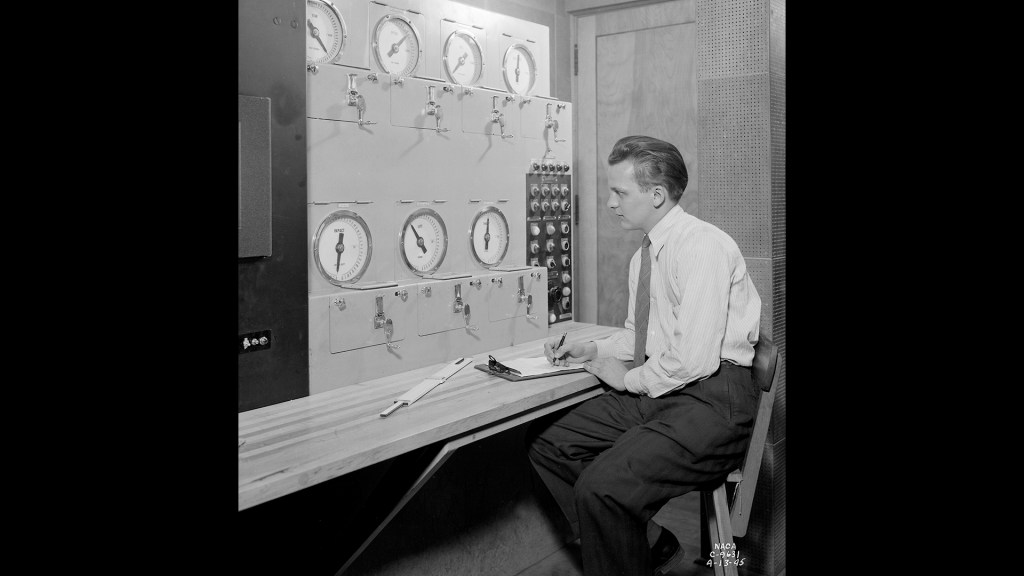 Researcher sits at Altitude Wind Tunnel Control Panel