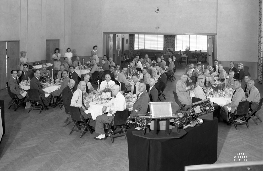 People sitting at round tables in auditorium.