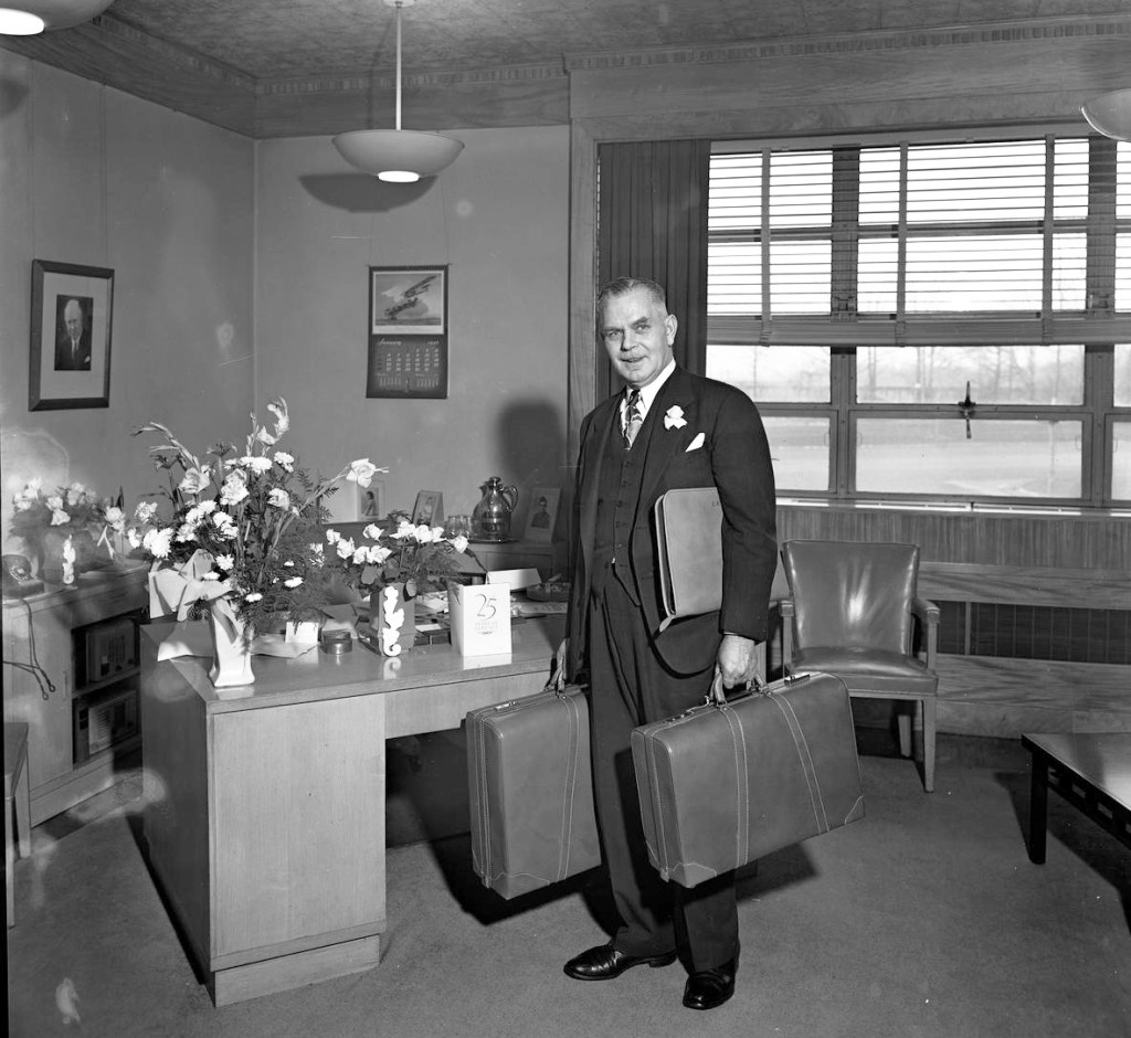 Man standing with suitcase in office.