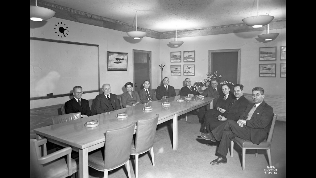Group of men sitting at long table.