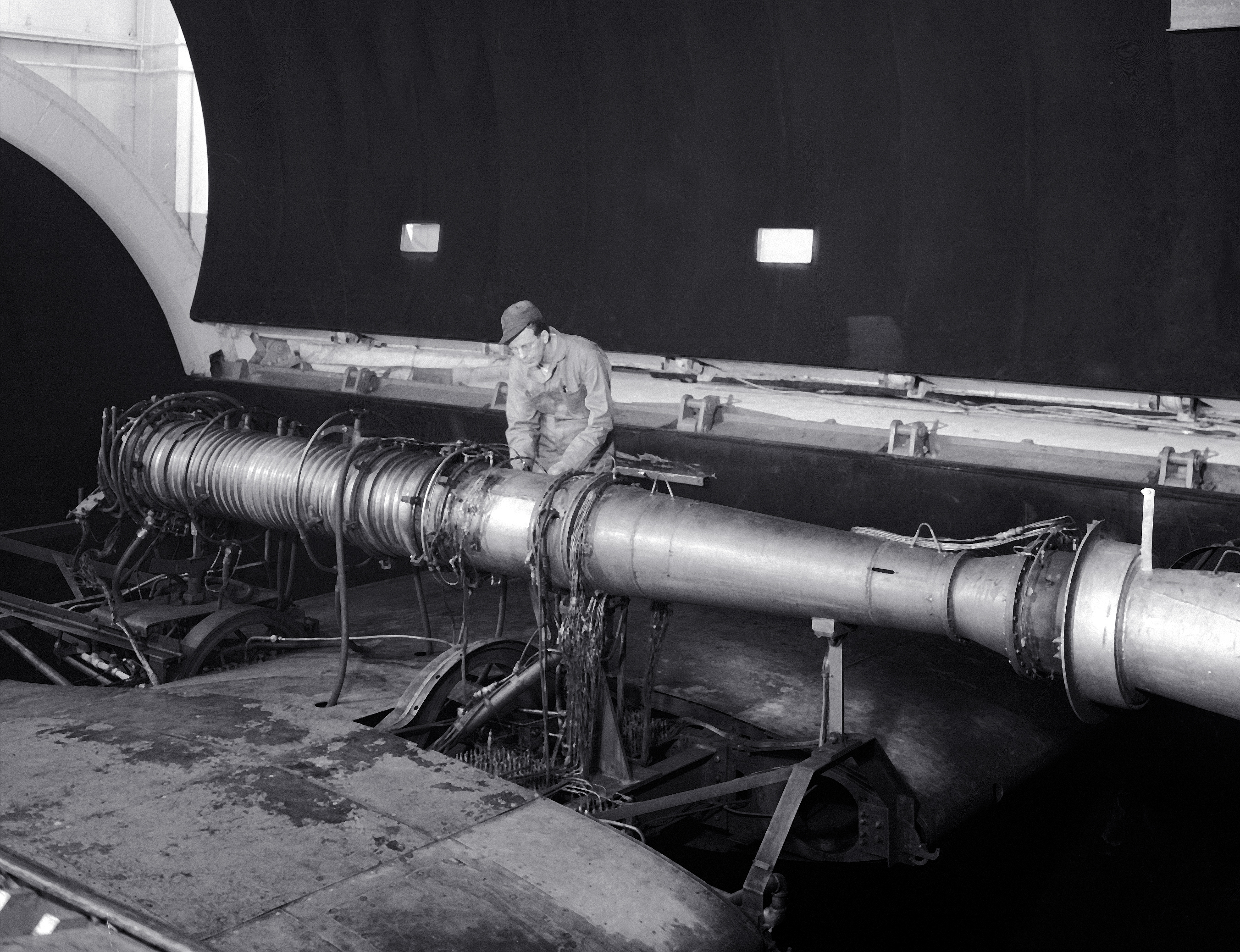 A mechanic stands beside ramjet engine in AWT test section