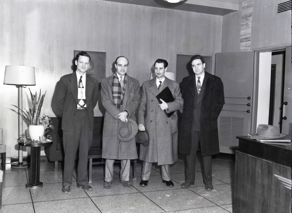Four men standing in lobby.