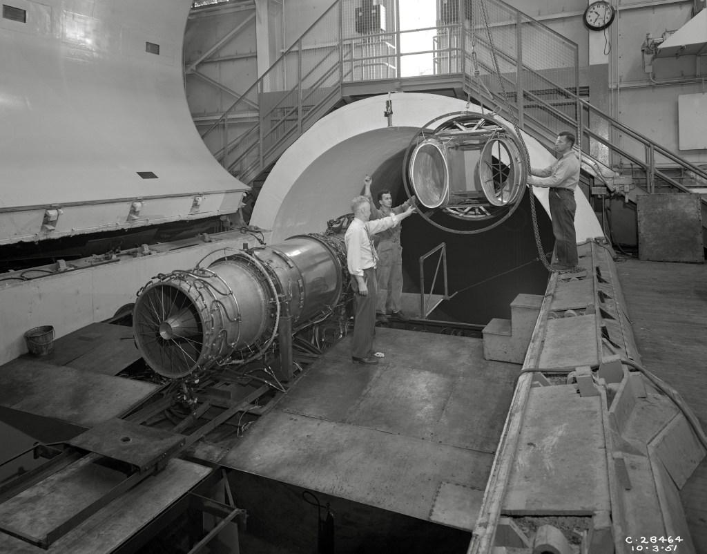 A rail crane lowers an inlet duct into the 20-foot diameter AWT test section