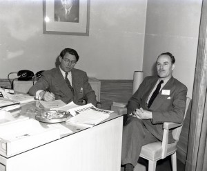 Two men sitting a desk.