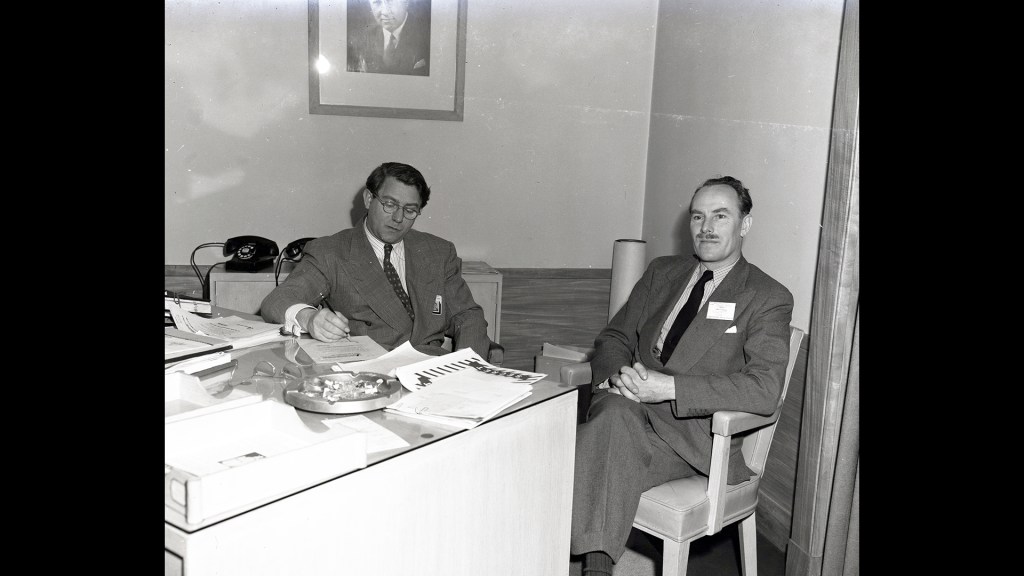 Two men sitting a desk.