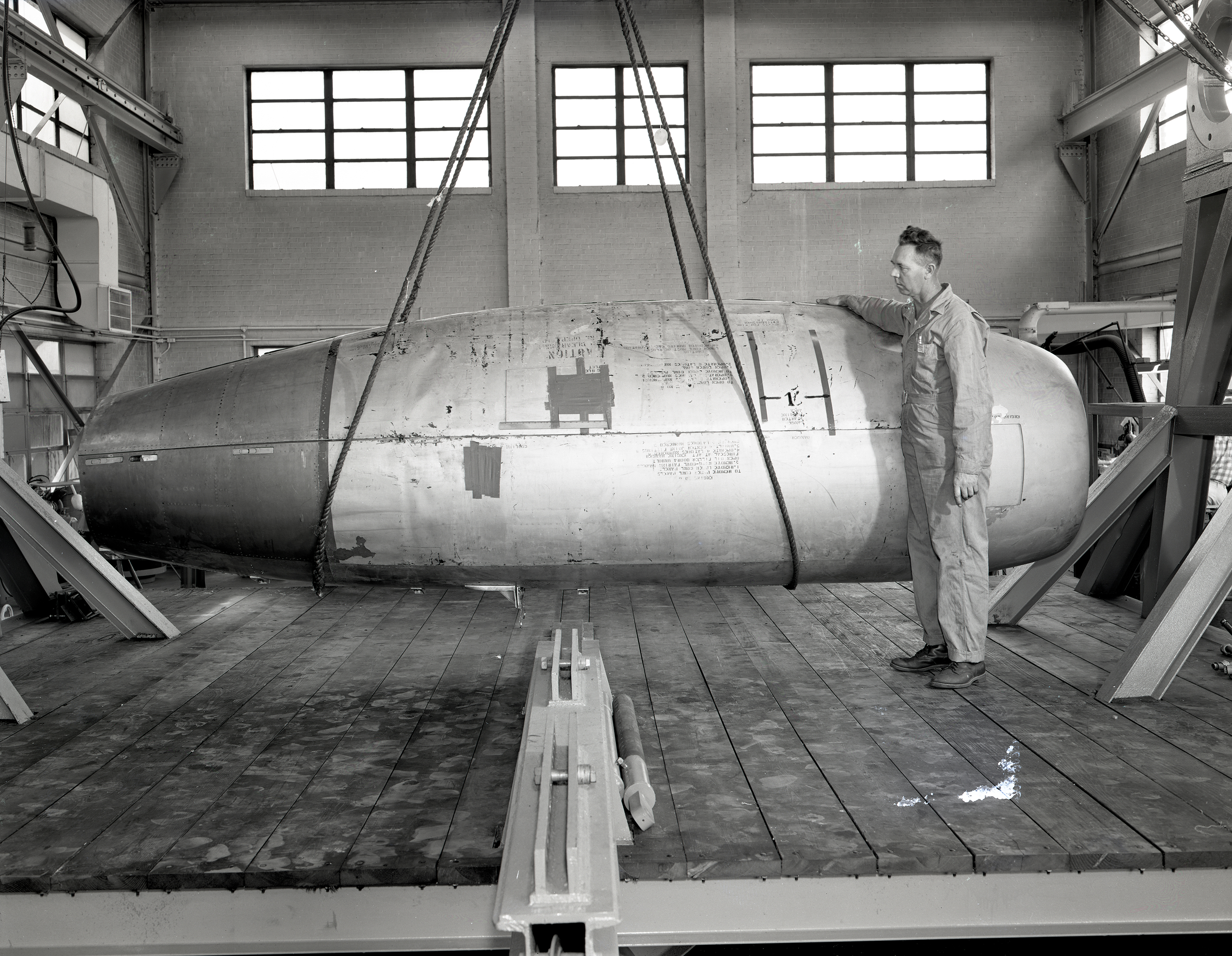 Mechanic with Allison J-71 Engine suspended by crane in AWT High-bay