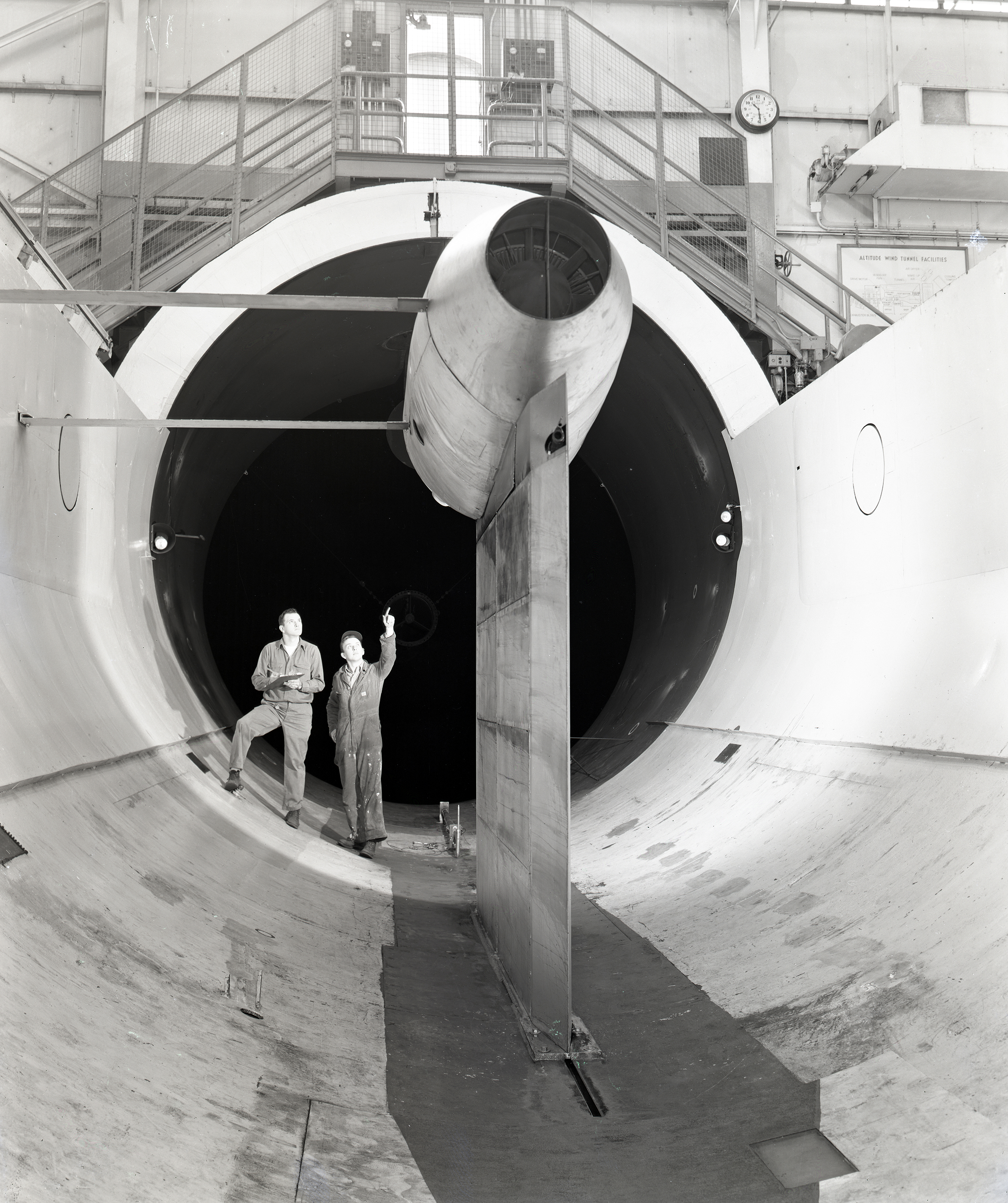 Technicians examine Pratt & Whitney J57 engine installed in the Altitude Wind Tunnel test section.