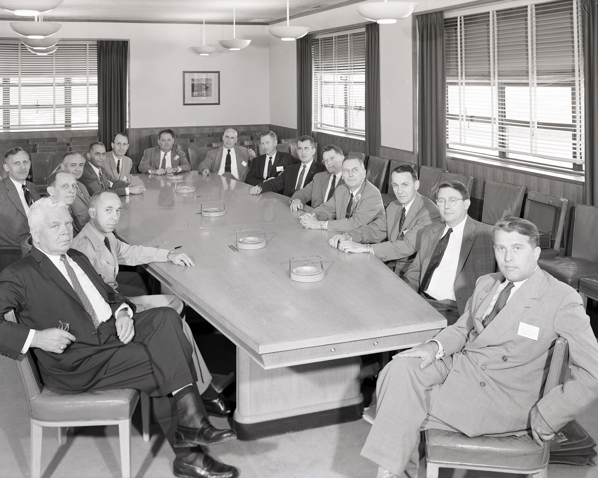 Group of men seated at conference table.