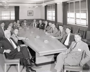 Group of men seated at conference table.
