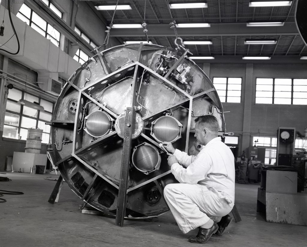 A technician working on control package of a Mercury capsule in shop