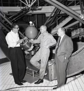Three men standing casually on platform.