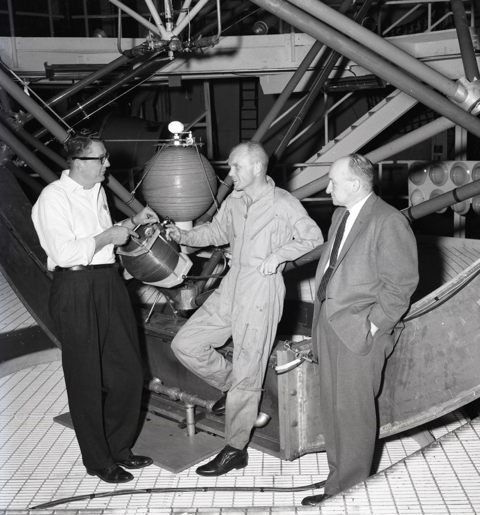 Three men standing casually on platform.