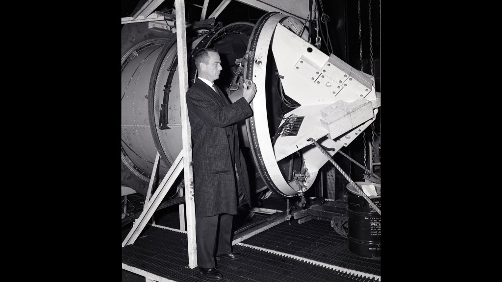 Scott Carpenter examining setup for capsule separation tests.