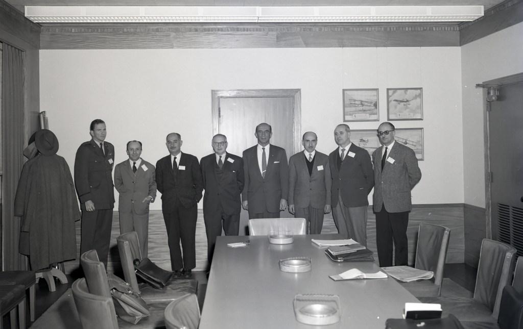 Group of men standing at end of table.