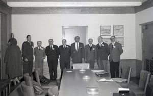 Group of men standing at end of table.
