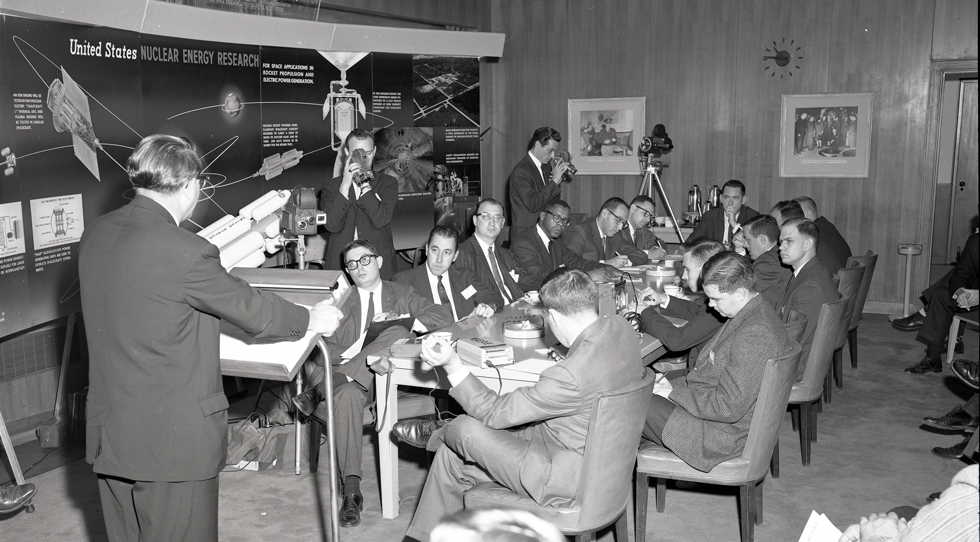 Man addressing people seated at table.