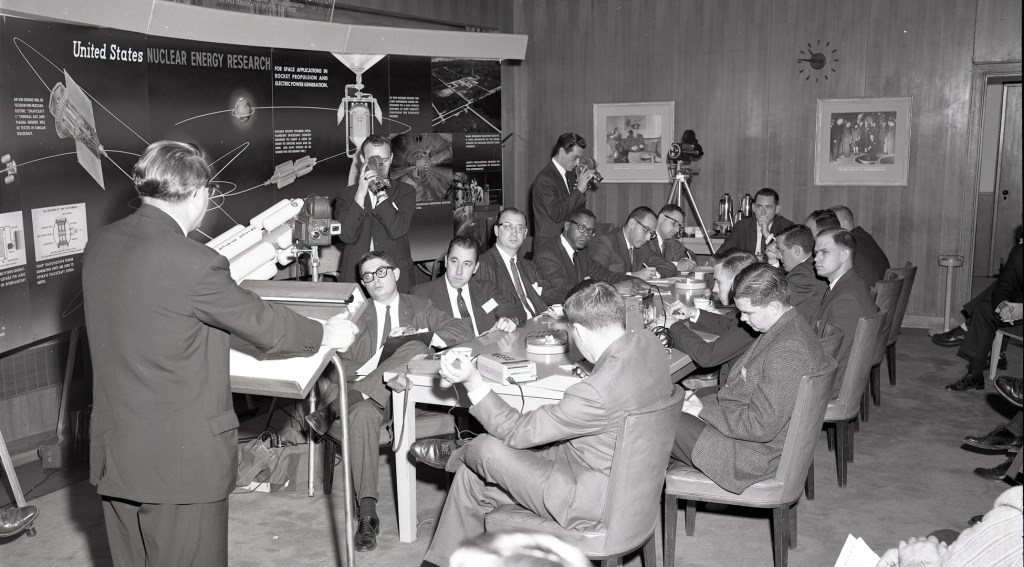 Man addressing people seated at table.