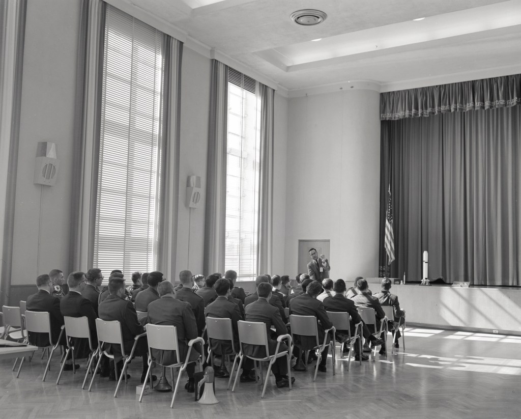 People seated in rows in auditorium.