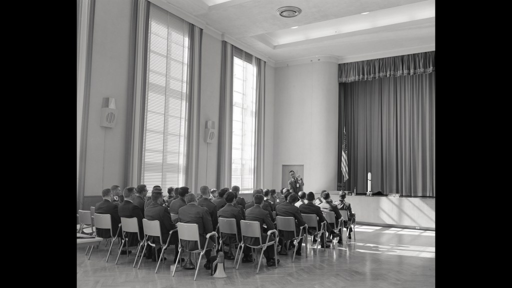 People seated in rows in auditorium.