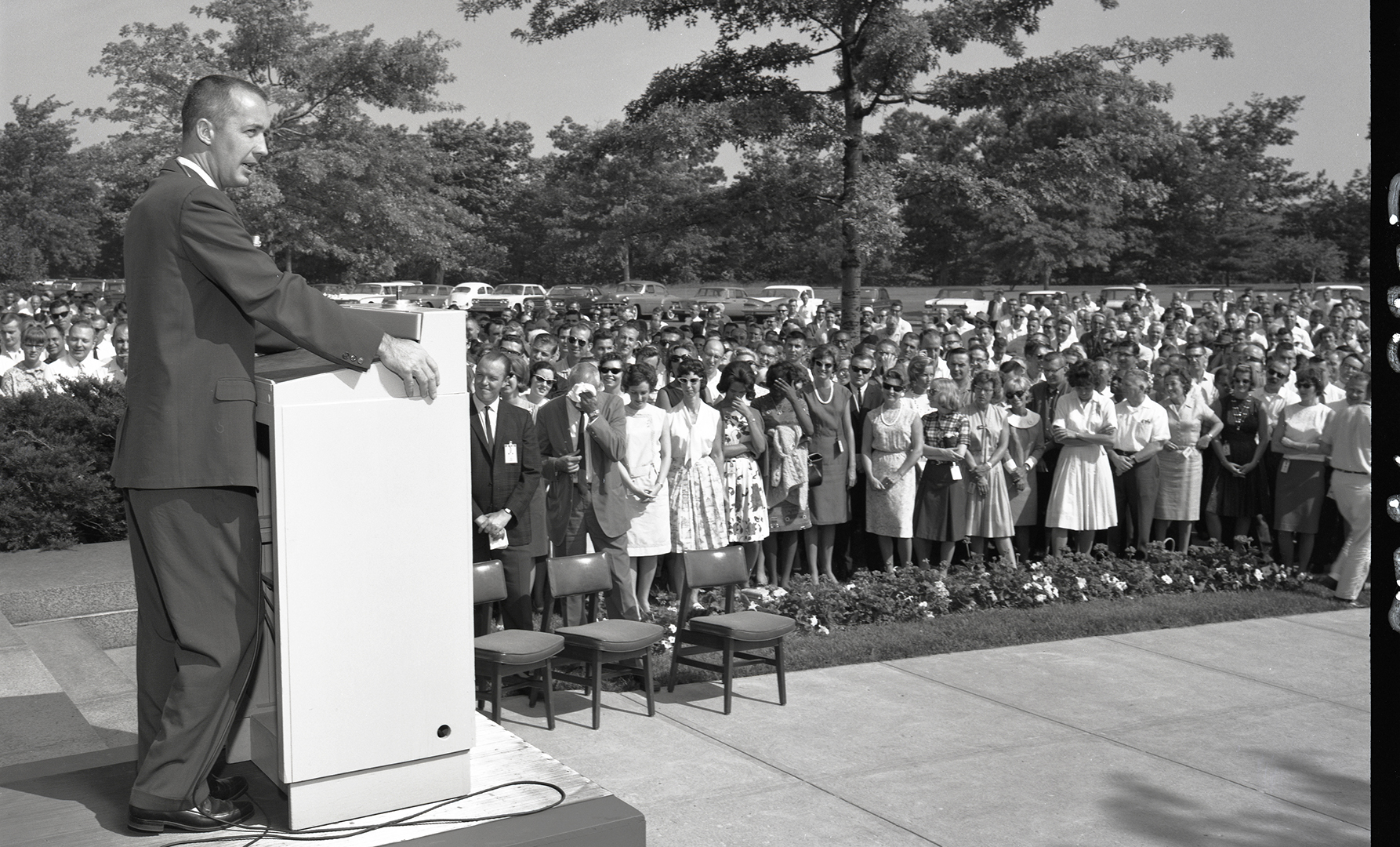 Man speaking to crowd outside building.