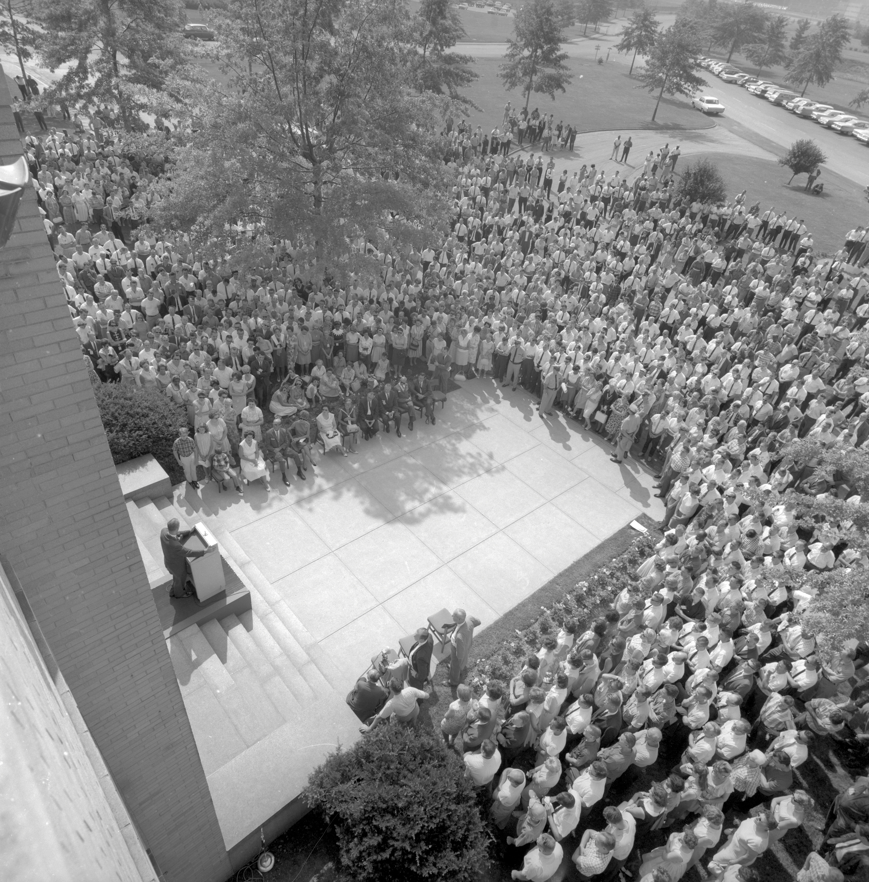 View down onto crowd outside building listening to speaker.