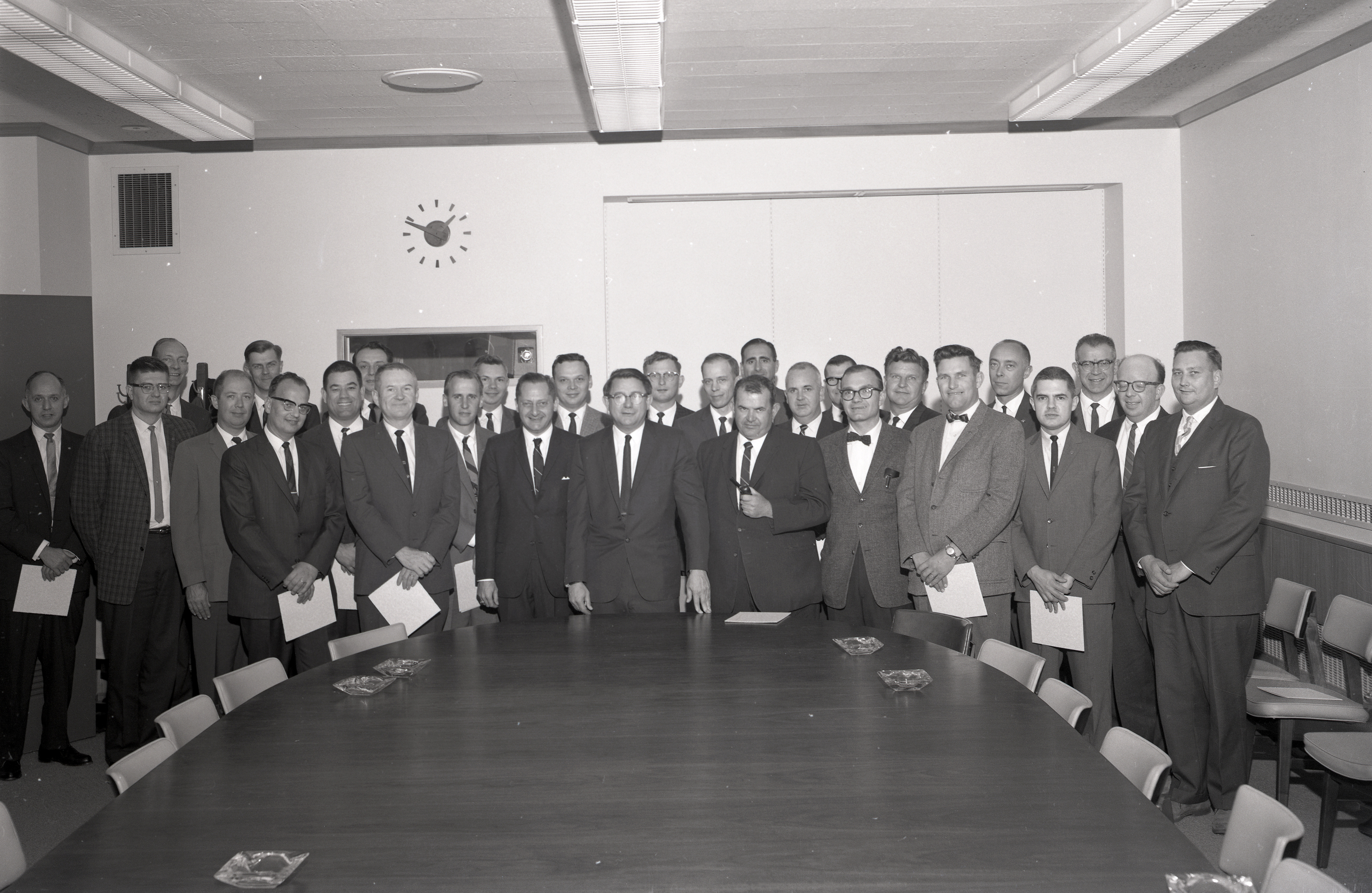 Group of men standing at end of table.