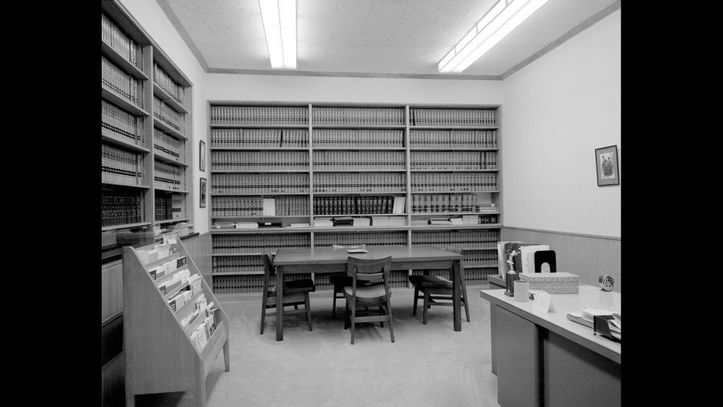 Interior of a small library with walls of books and a table for reading