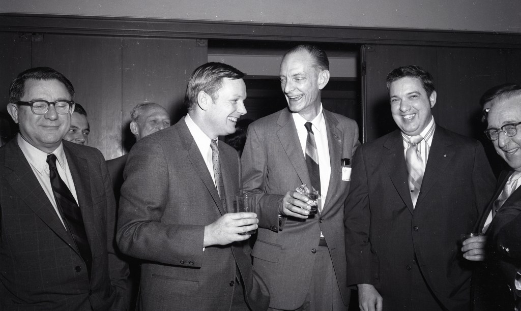 Men greeting one another in auditorium.