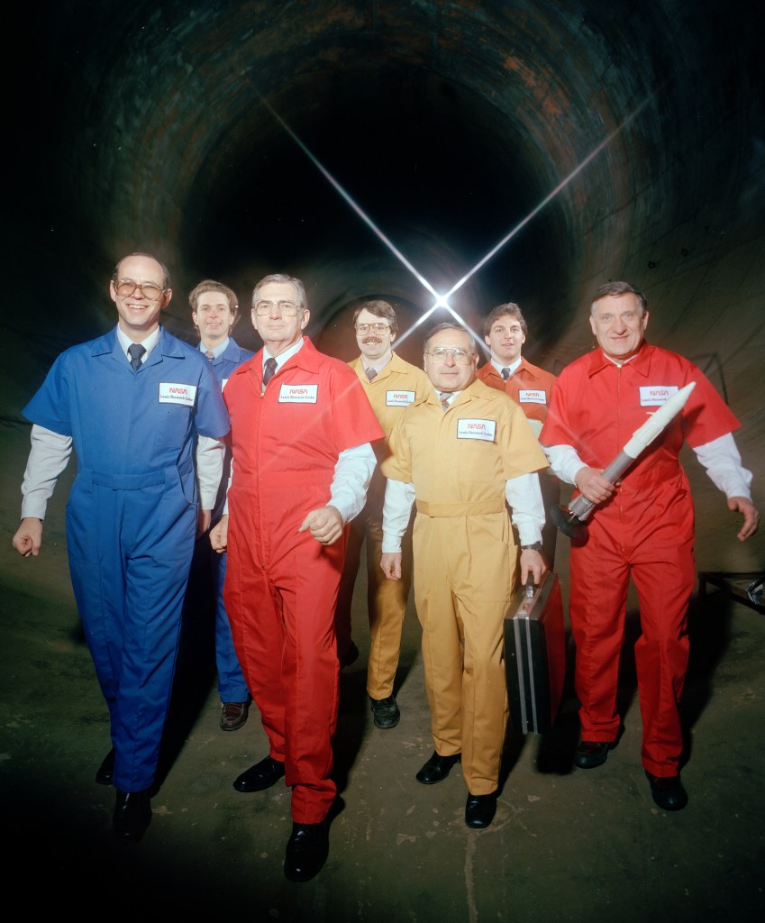 Members of AWT team in jumpsuits superimposed of interior shot of the tunnel