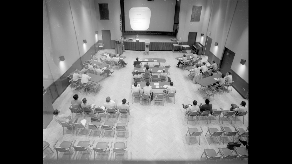 View from above of people at tables in auditorium.