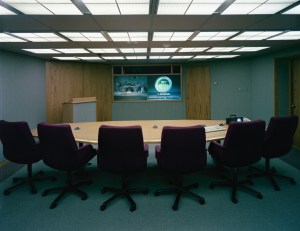 Table with chairs in front of wall-mounted screens.