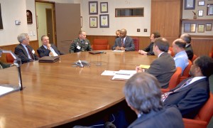 People sitting around oval conference table.