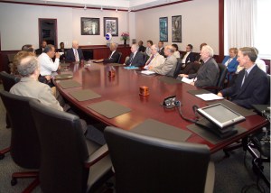 People sitting around oval conference table.