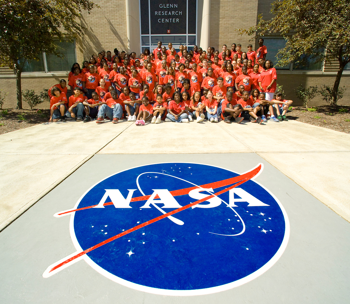 Group of students outside viewing NASA logo.