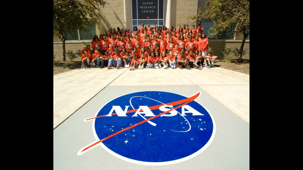 Group of students outside viewing NASA logo.