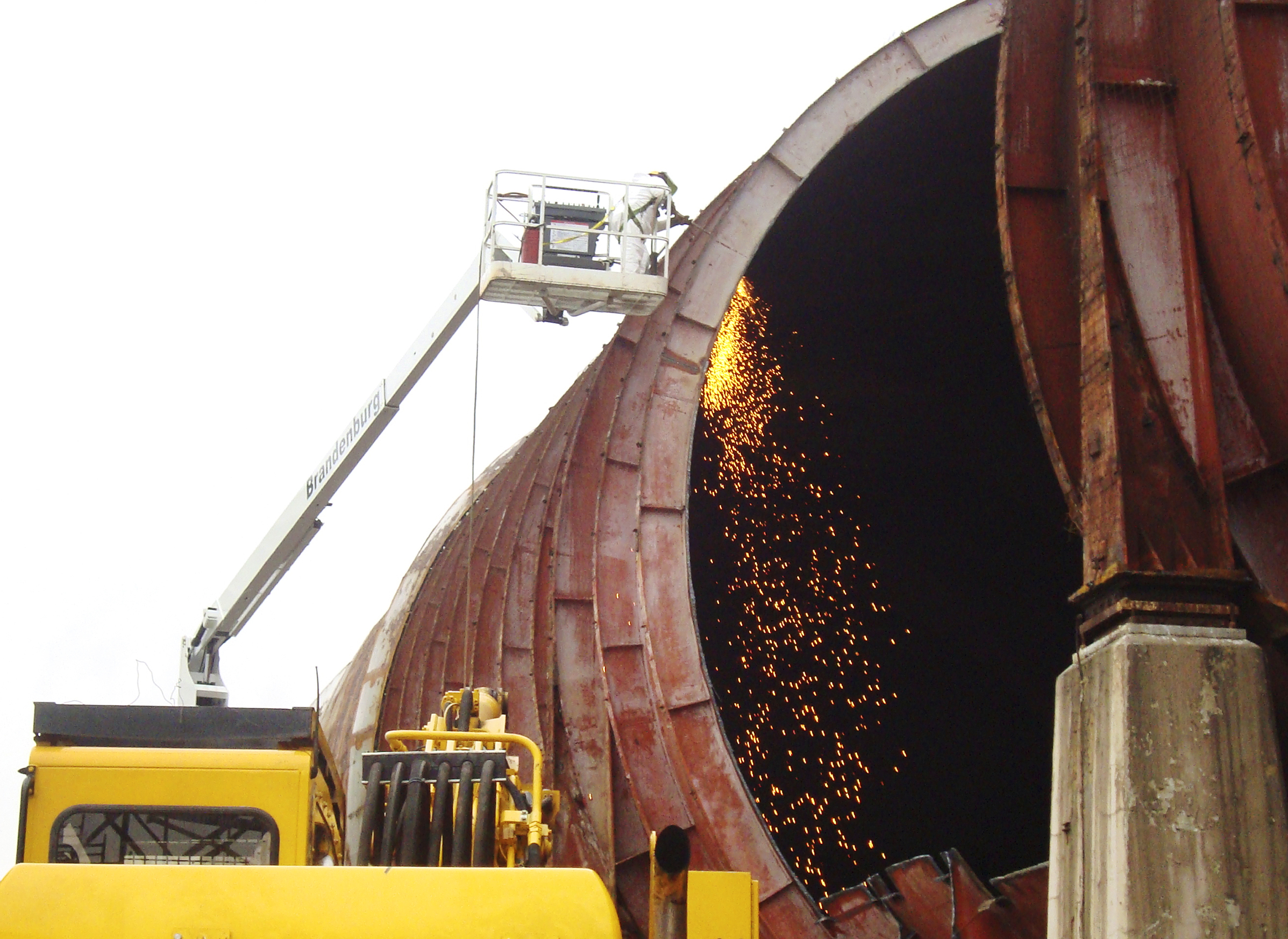 Man in lift with torch cutting tunnel shell