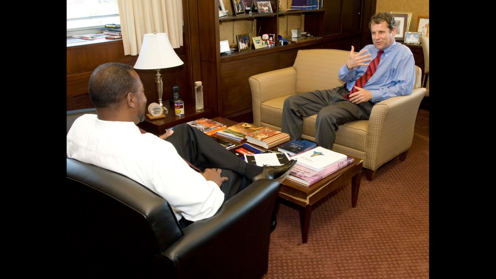 Two men sitting in chairs talking.