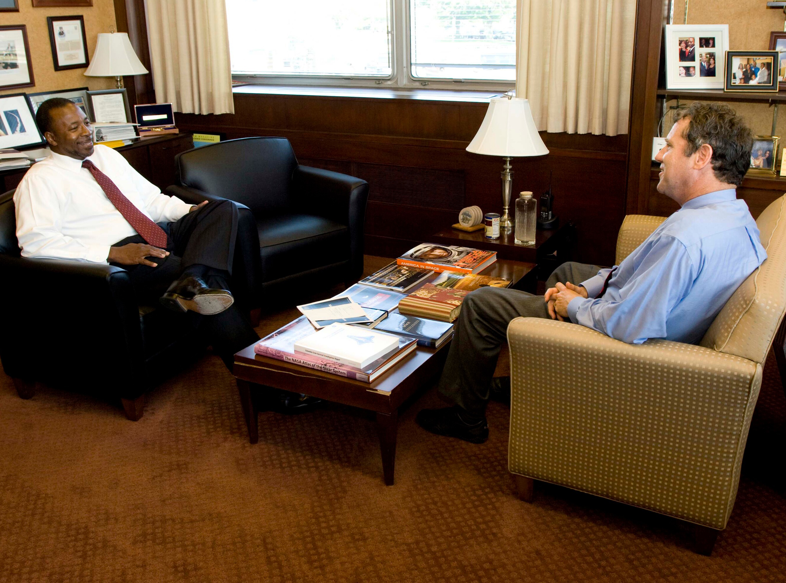 Two men seated in chairs in office.