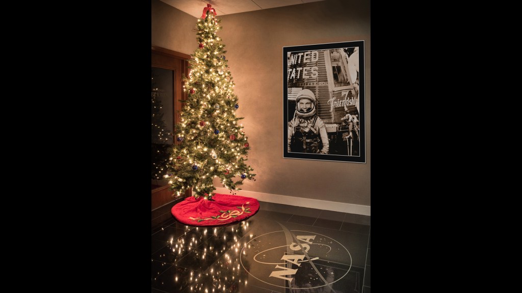 Christmas tree next to John Glenn poster.