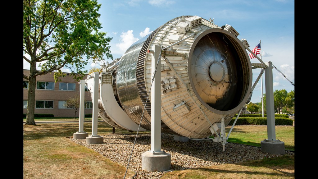 Rocket stage on display outside building.