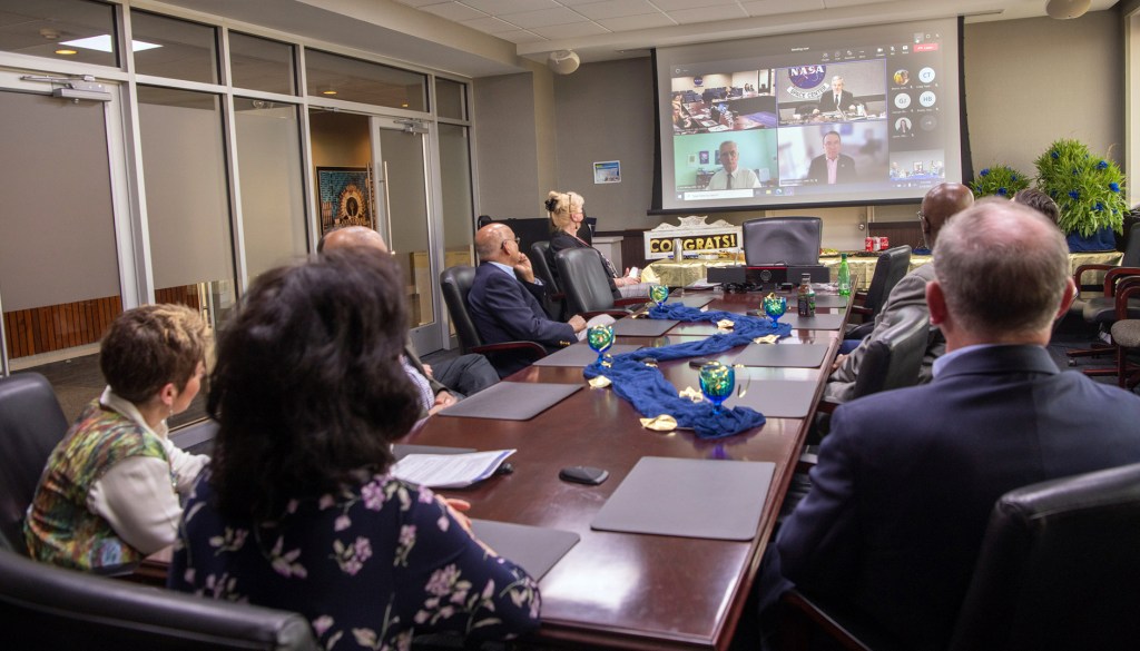 People in conference room watching screen.