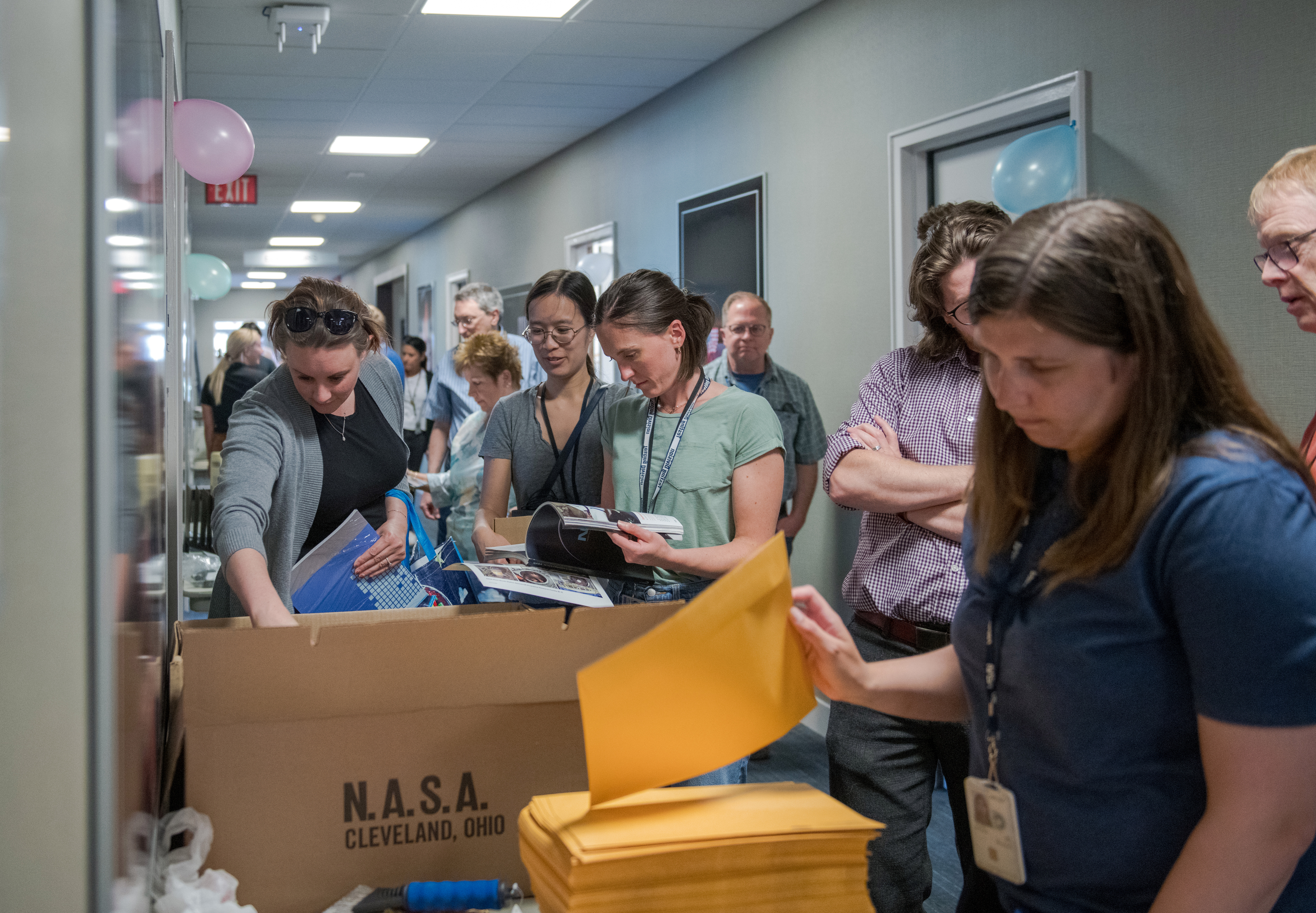 Crowded hallway with people looking at items.