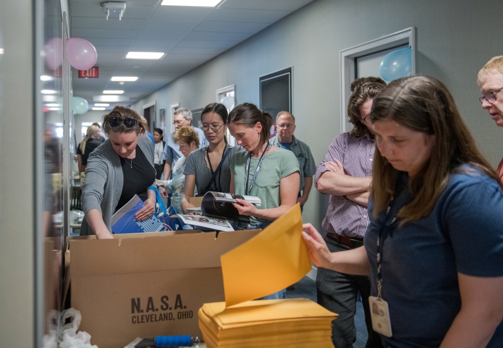 Crowded hallway with people looking at items.