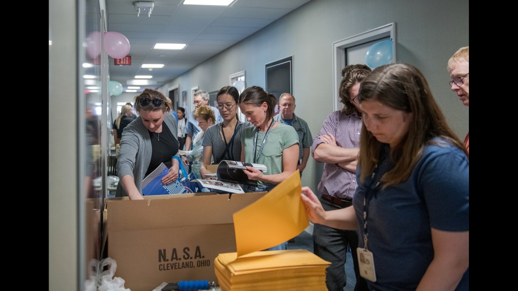 Crowded hallway with people looking at items.