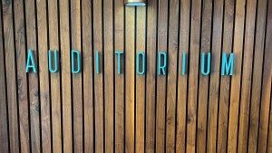 Blue letters spelling "Auditorium" on wood wall.