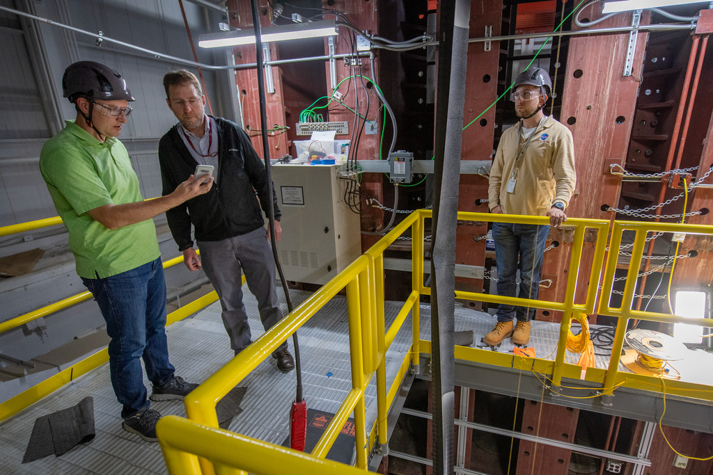 Researchers look at a bend that occurred in a 94-foot triangular, rollable and collapsible boom during an off-axis compression test.