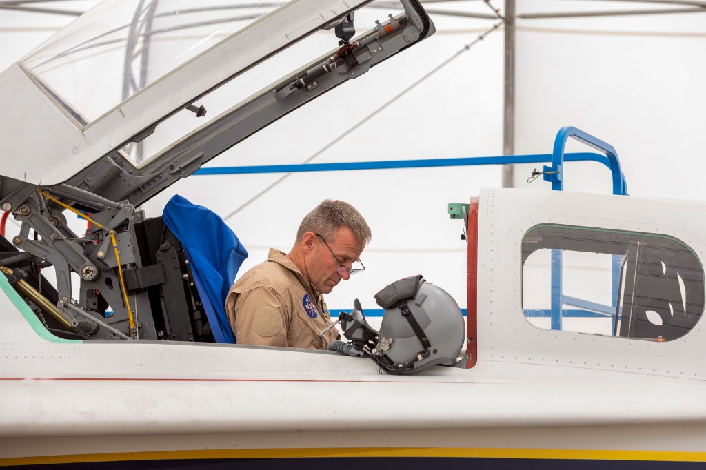 A NASA test pilot sits in the cockpit of a jet aircraft.