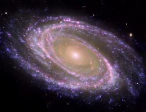 A spiral galaxy's winding arms are shades of pink and purple in this image. At the center is a bright, hazy yellow light.