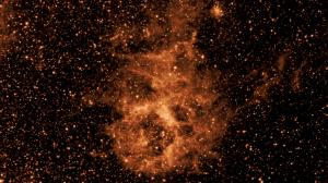 Infrared image showing a field of copper stars with a distinct smoke-like cloud at the center.